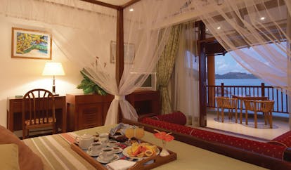 Domaine de la Reserve Seychelles room service tray on bed four poster bed balcony ocean view
