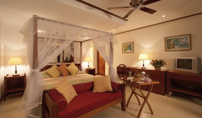 Domaine de la Reserve Seychelles white bedroom four poster white drapes ottoman room service
