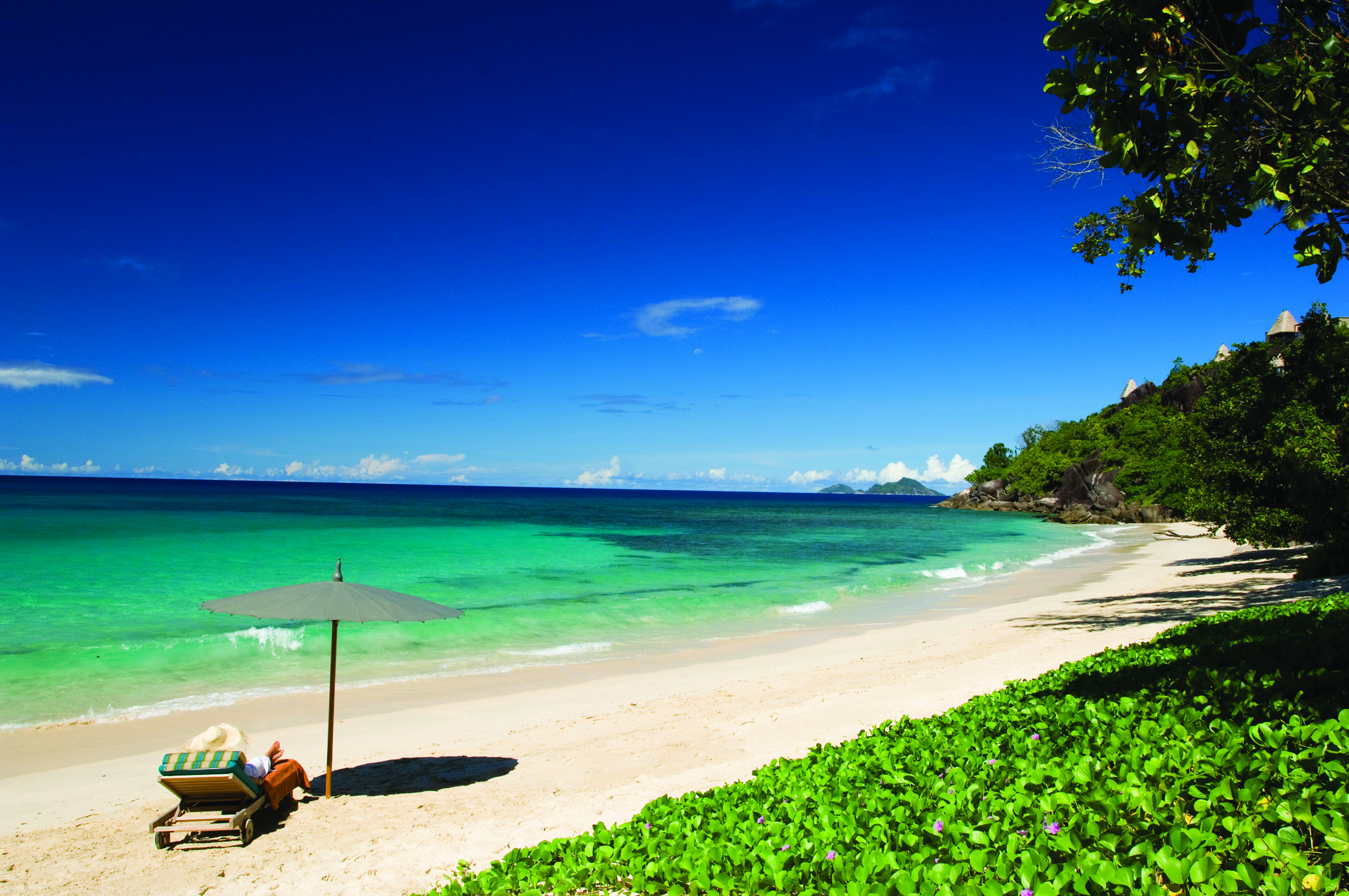 Maia Seychelles beach white sand clear blue waters sun lounger umbrella