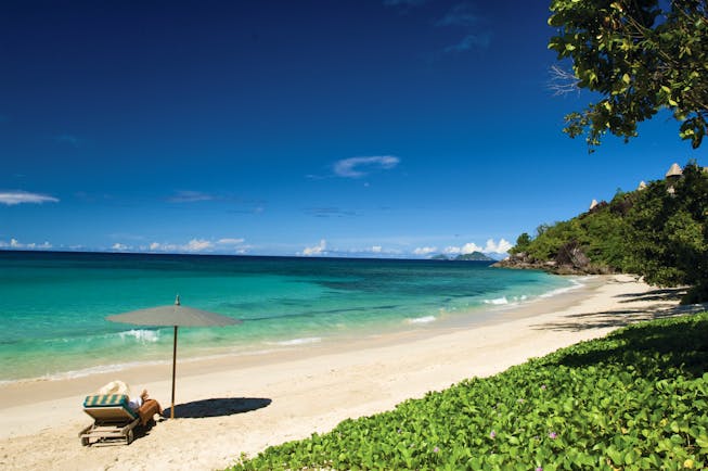 Maia Seychelles beach white sand clear blue waters sun lounger umbrella