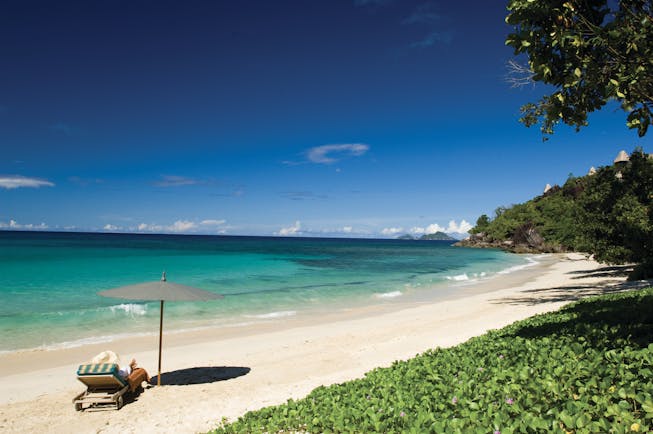 Maia Seychelles beach white sand clear blue waters sun lounger umbrella