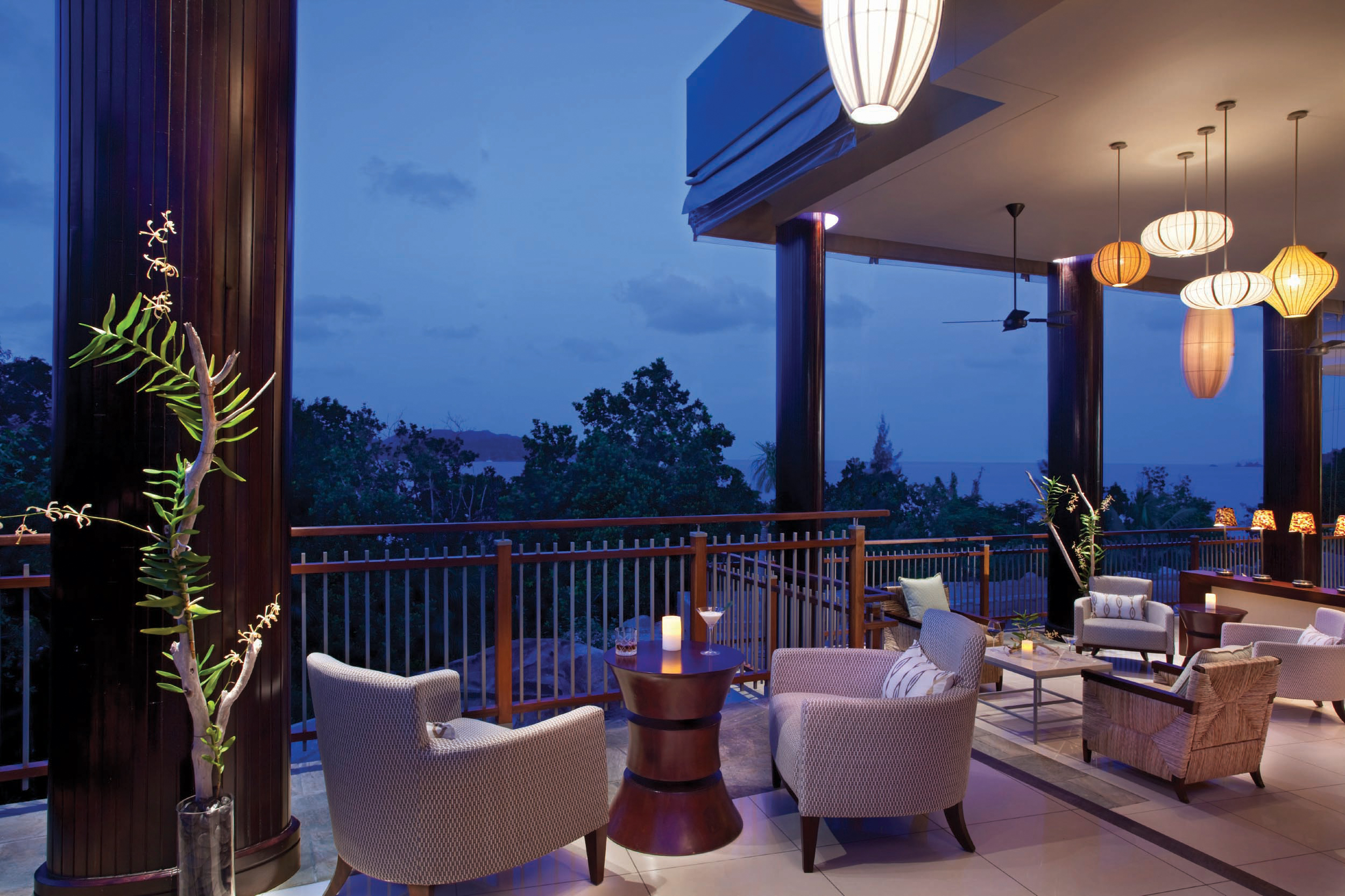 Outdoor bar with arm chairs set out for seating and covered porch area with chandelier hanging down 