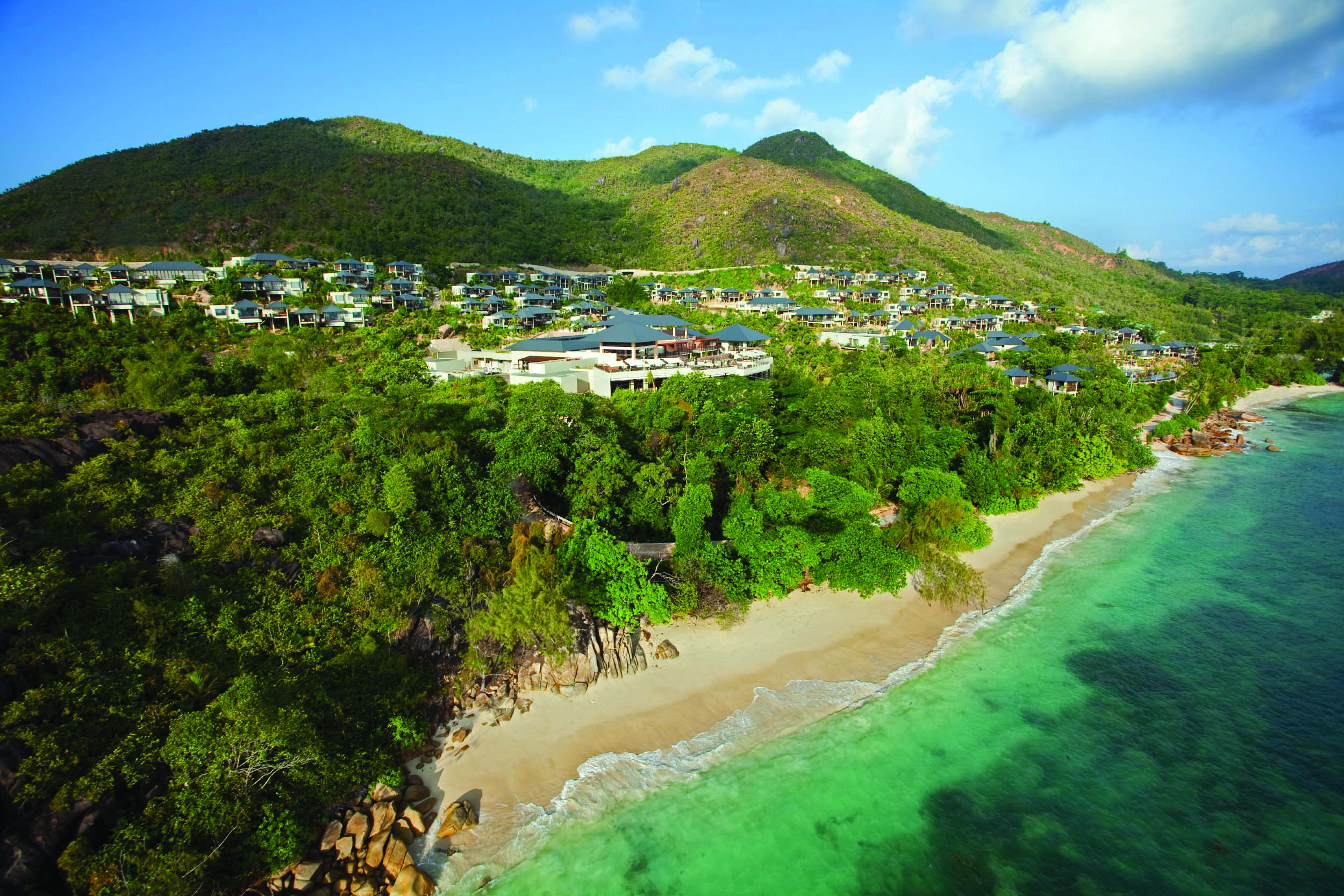 Raffles Praslin resort aerial shot, beach, villas nestled amongst tropical greenery