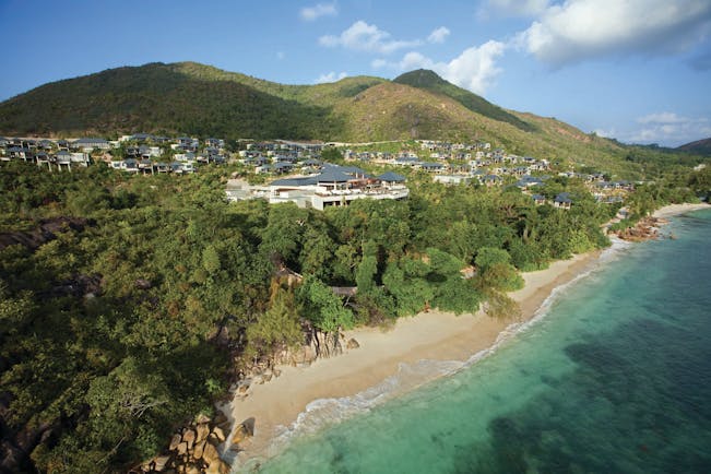 Raffles Praslin resort aerial shot, beach, villas nestled amongst tropical greenery