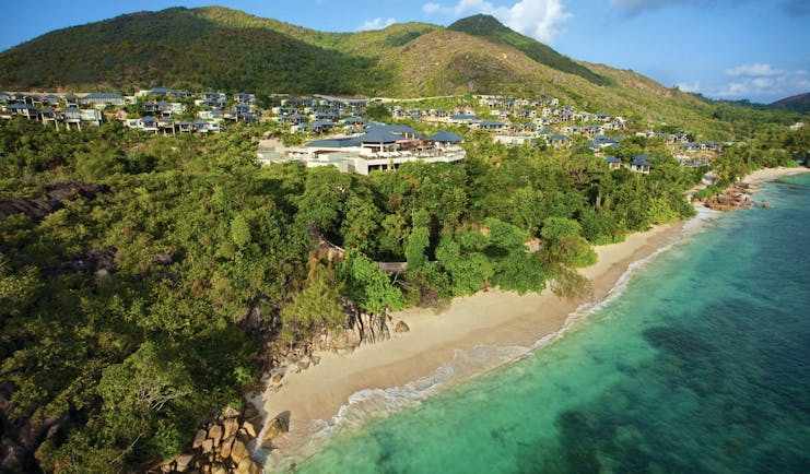Raffles Praslin resort aerial shot, beach, villas nestled amongst tropical greenery