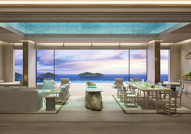 Six Senses Zil Pasyon residence lounge, modern decor, large dining table and sofa, glass walls with views across the ocean to adjacent islands