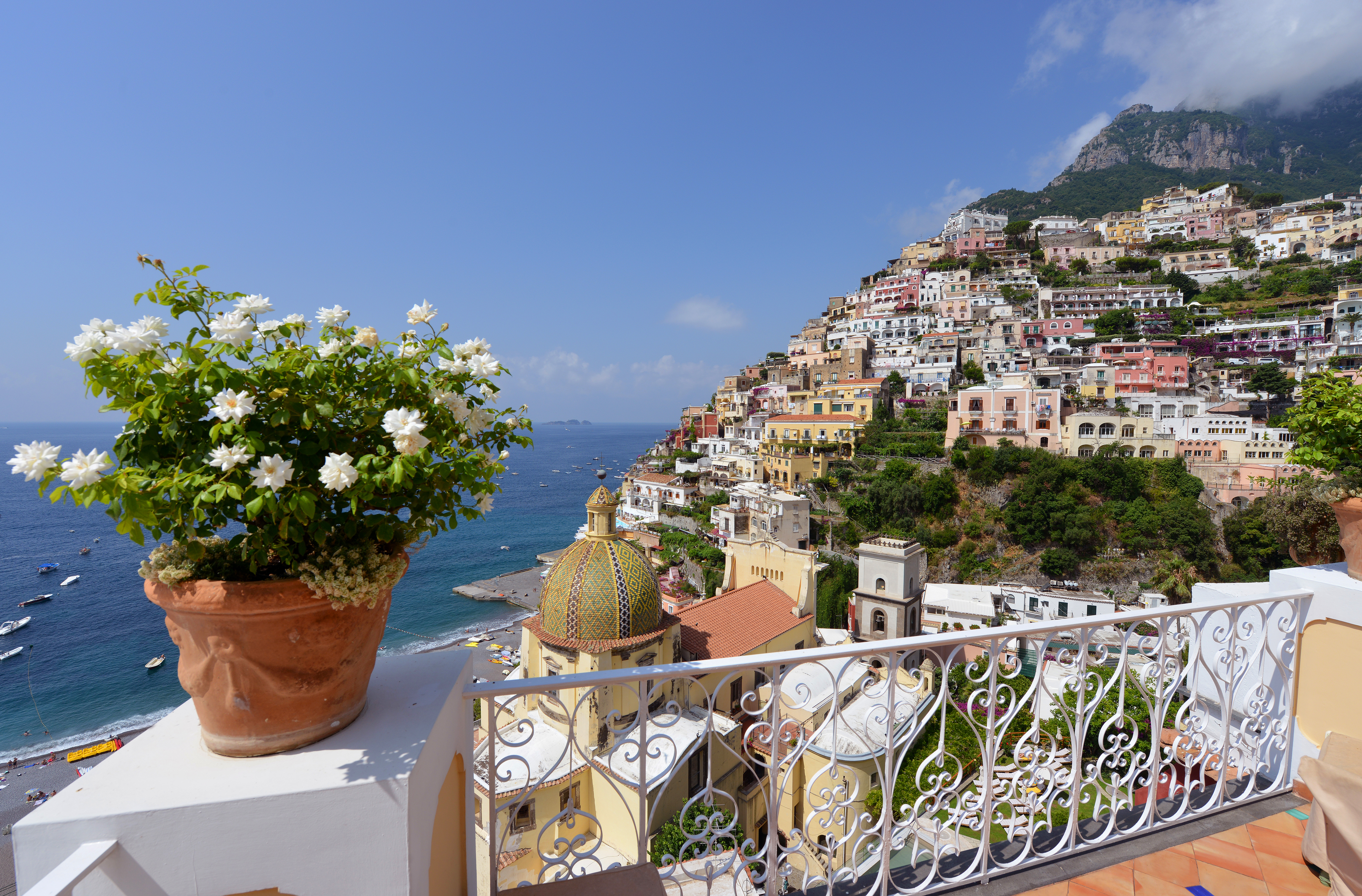 White flowers in terracotta pot on balcony overlooking houses below in Positano