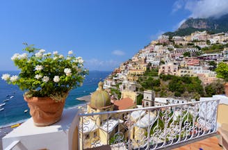 White flowers in terracotta pot on balcony overlooking houses below in Positano