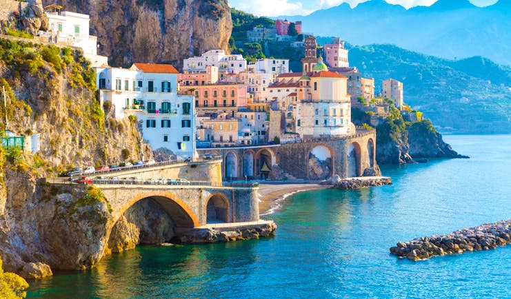 White buildings with red and orange roofs of the houses in Amalfi lining the seafront