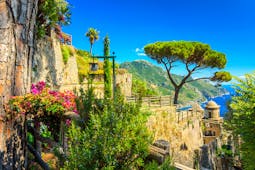 Umbrella pine and flowers and plants in stone terraces of the Villa Rufolo in Ravello with the sea in the distance
