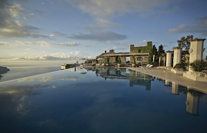 Hotel Caruso Amalfi Coast infinity pool area cky reflecting in pool water seating area