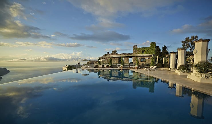 Hotel Caruso Amalfi Coast infinity pool area cky reflecting in pool water seating area