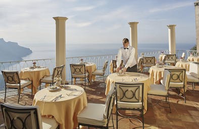 Hotel Caruso Amalfi Coast restaurant terrace waiter dining tables chairs overlooking the sea