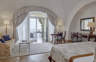 Hotel Caruso Amalfi Coast suite bed and living area doors leading to balcony