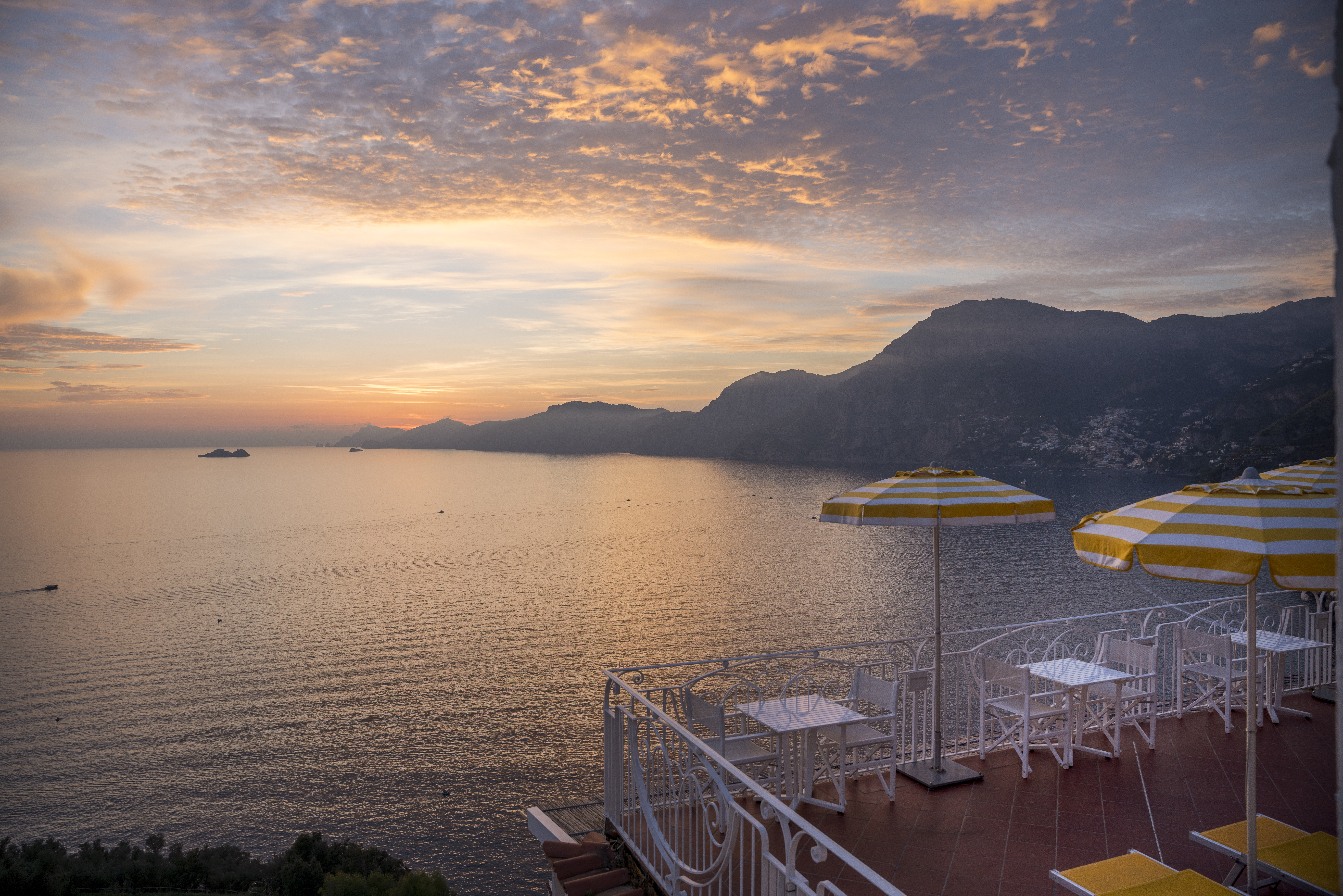 Hotel Tramonto d'Oro terrace at sunset, with tables and sun loungers overlooking the sea and the rocky coast