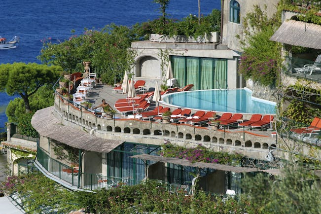 Overview of the terrace swimming pool, with red umbrellas and deck chairs shown surrounding the pool
