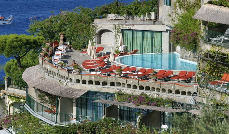 Overview of the terrace swimming pool, with red umbrellas and deck chairs shown surrounding the pool
