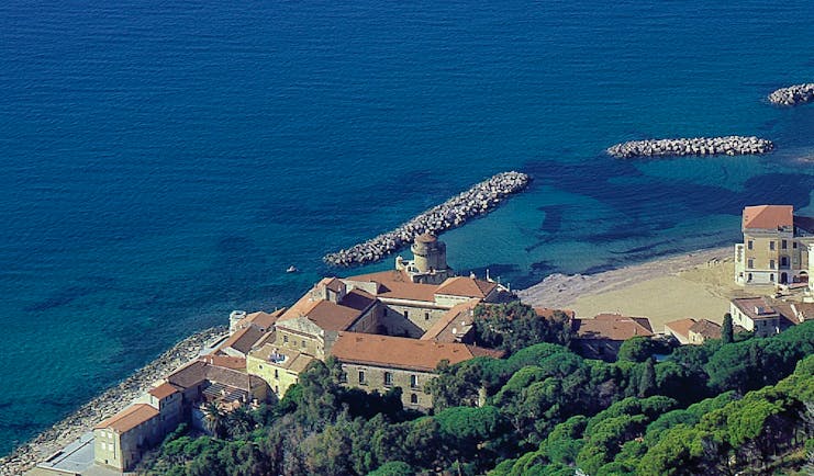 Aerial view of coast and hotel with green mountains in background behind
