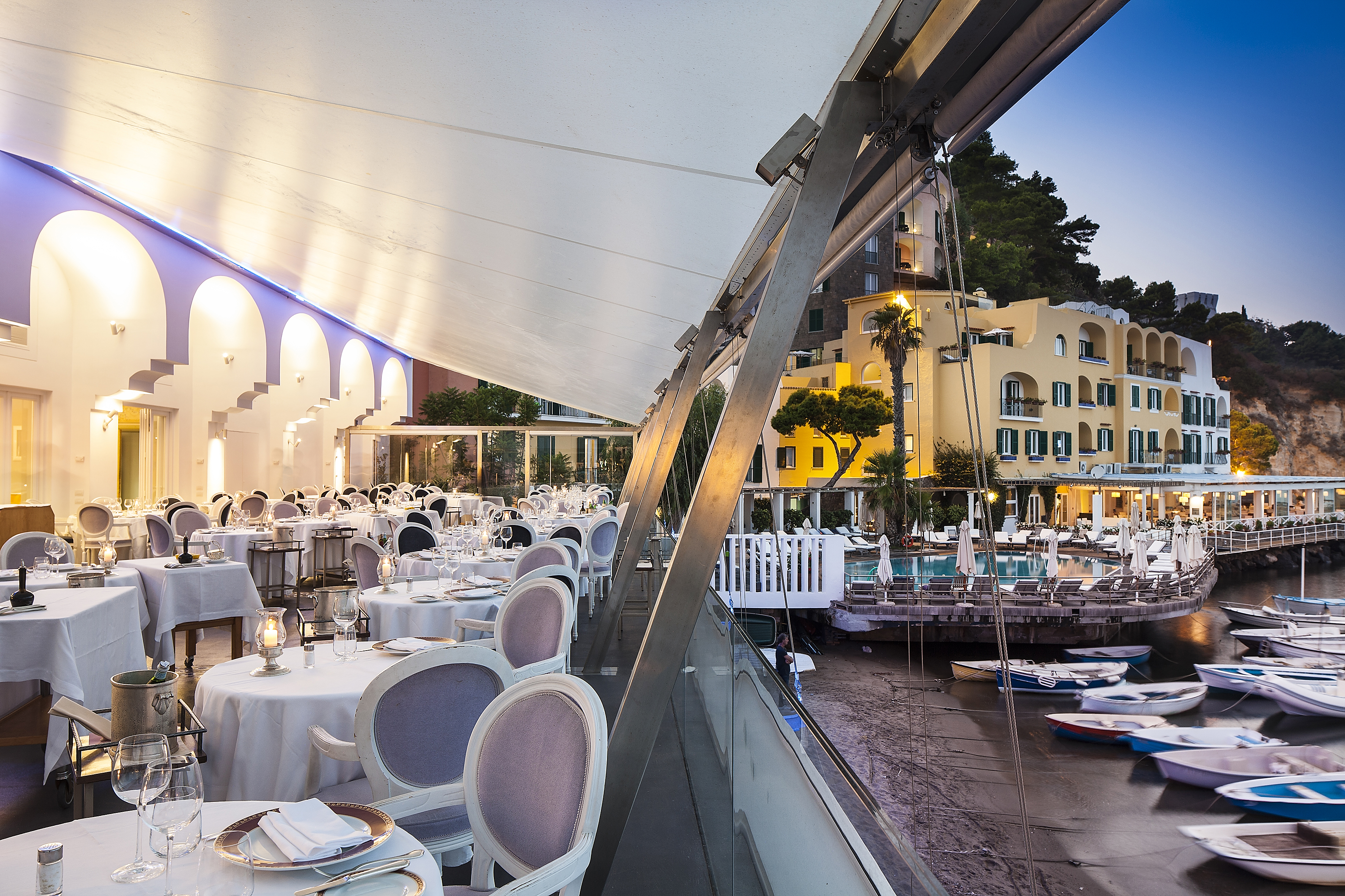 Regina Isabella restaurant, canopied dining area on shoreline, boats moored on sand, elegant tables and chairs