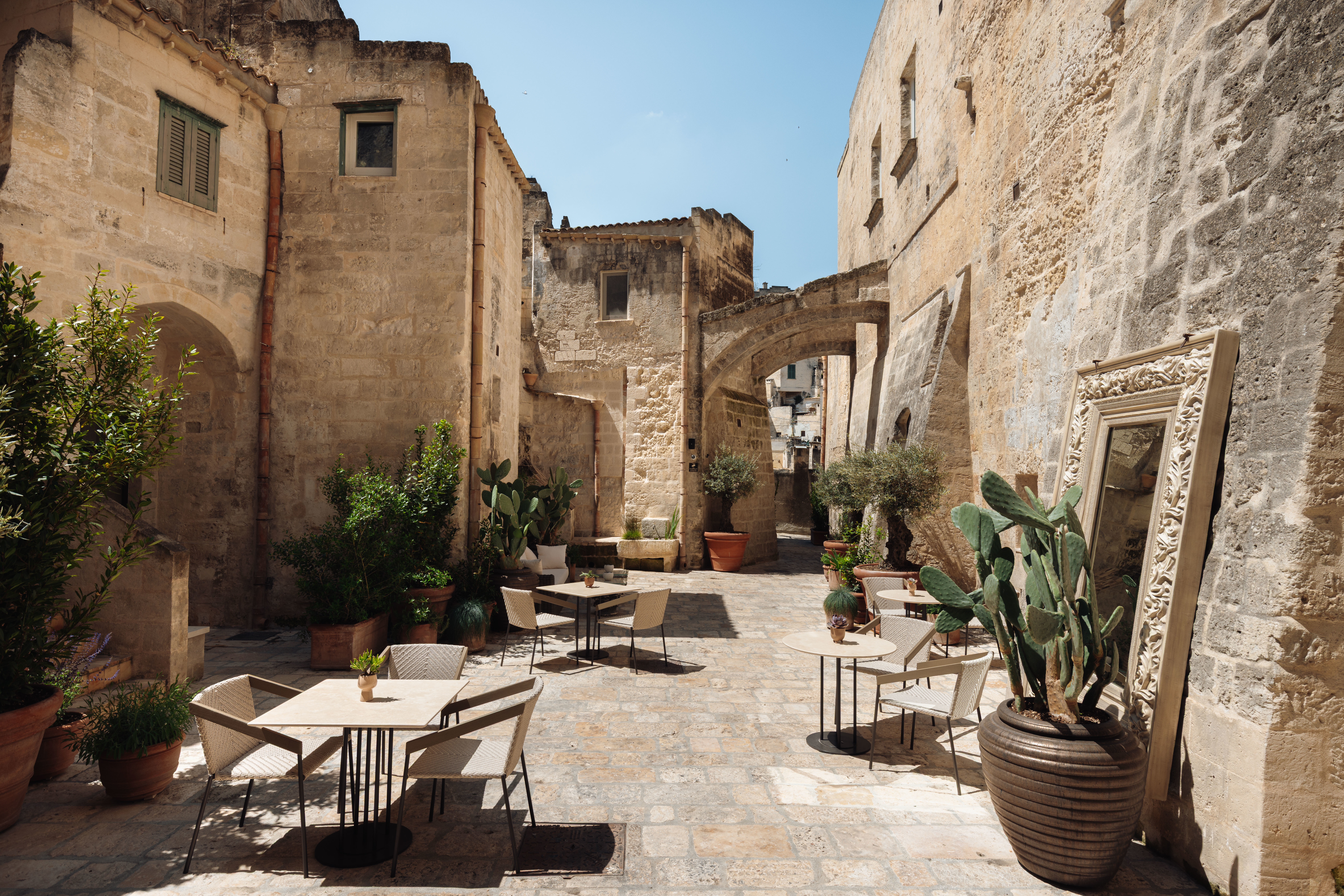 Vetera Matera courtyard, with characterful stone walls and archways on every side, and plants and tables in the centre