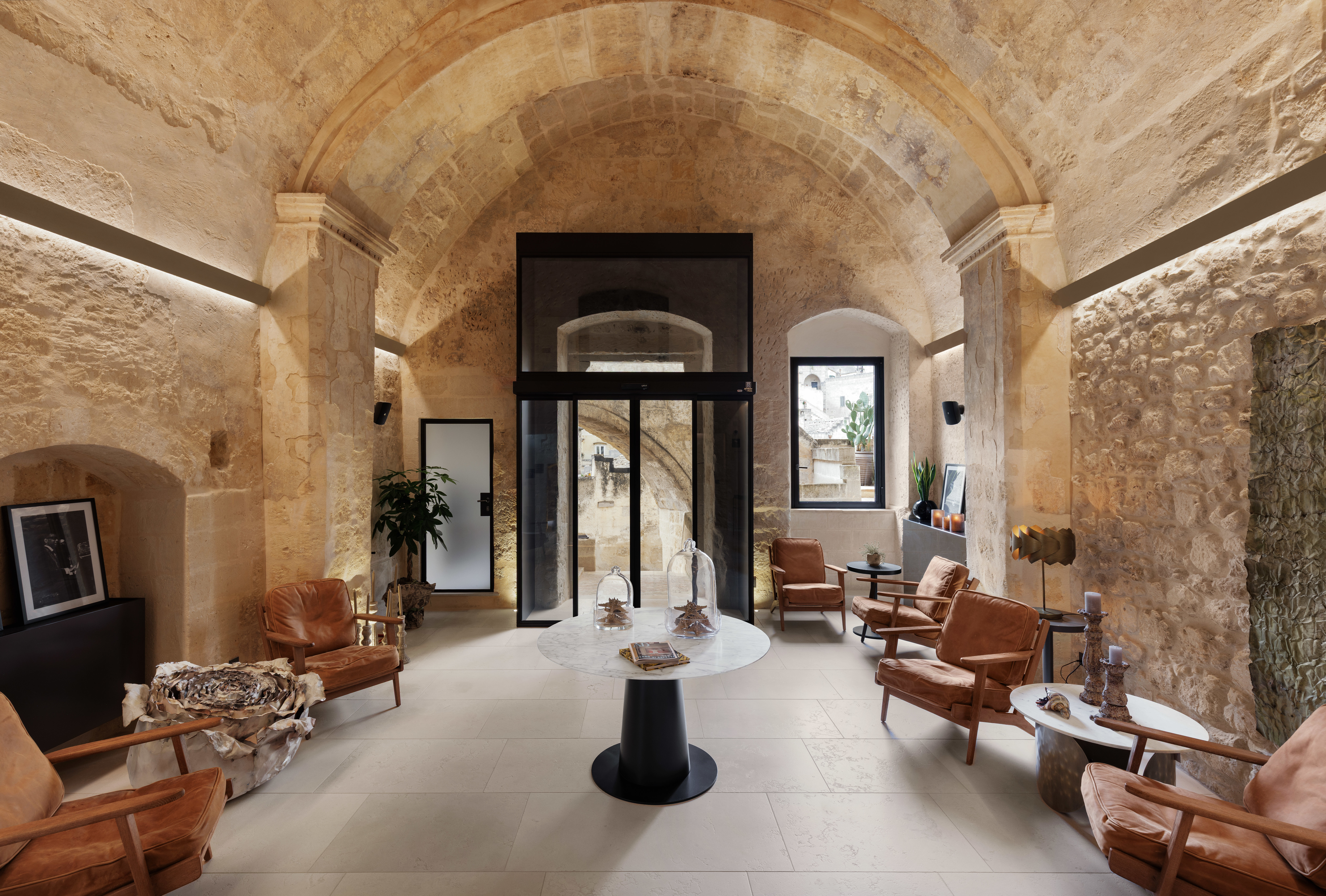 Vetera Matera reception, with curve stone ceiling, ochre-coloured low armchairs, strip lighting and modern furnishings