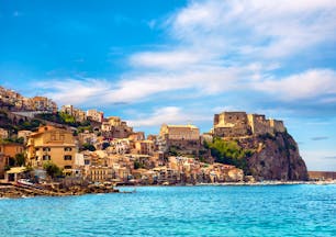 Castle perched on cliff near town overlooking bright blue sea at Scilla in Calabria