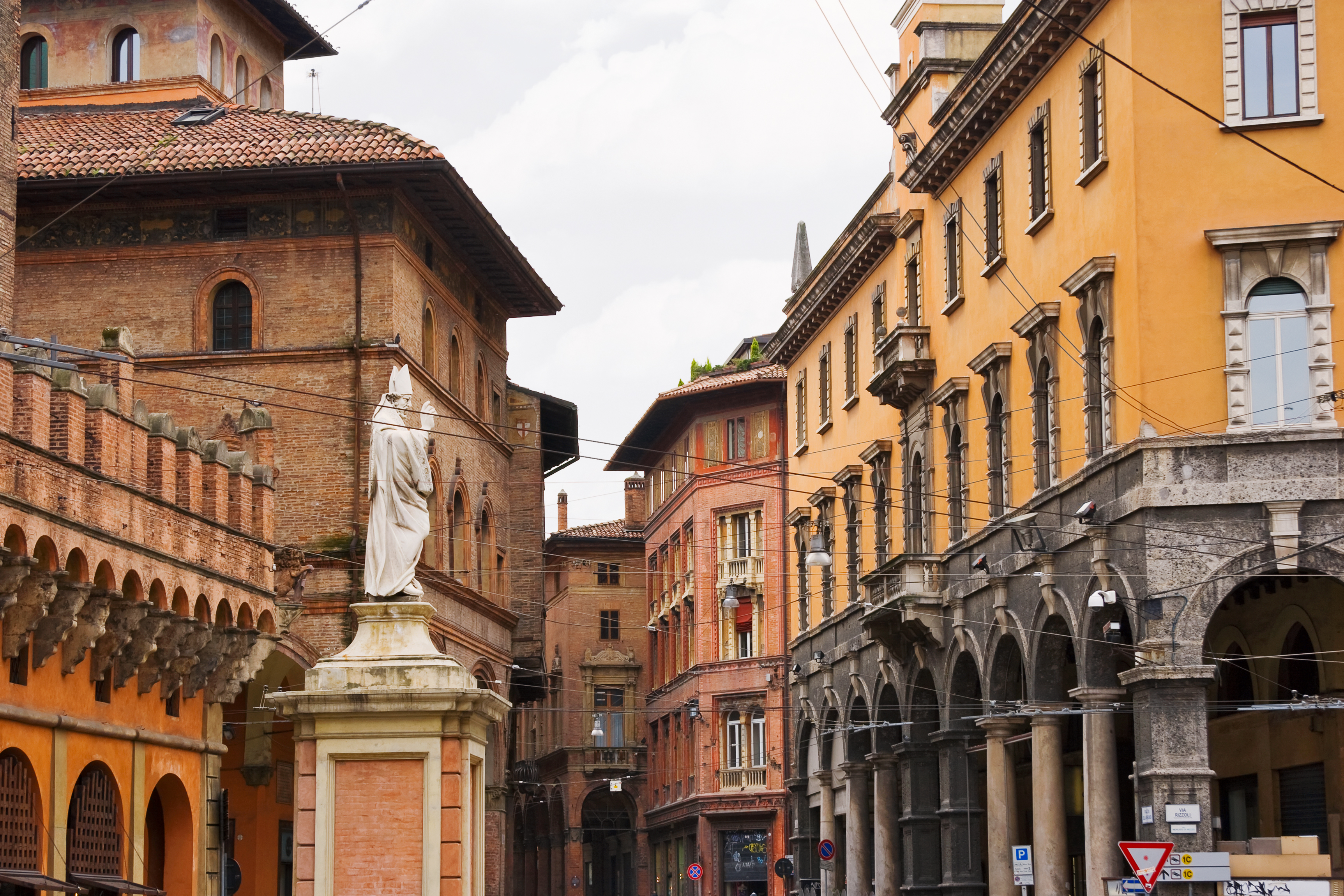 Ochre and reddish arcaded houses in street in Bologna