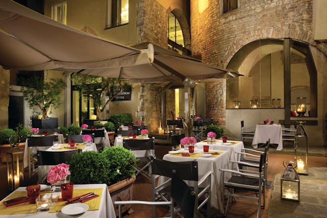 Hotel Brunelleschi Florence courtyard dining outdoor dining area tables set with candles pink flowers