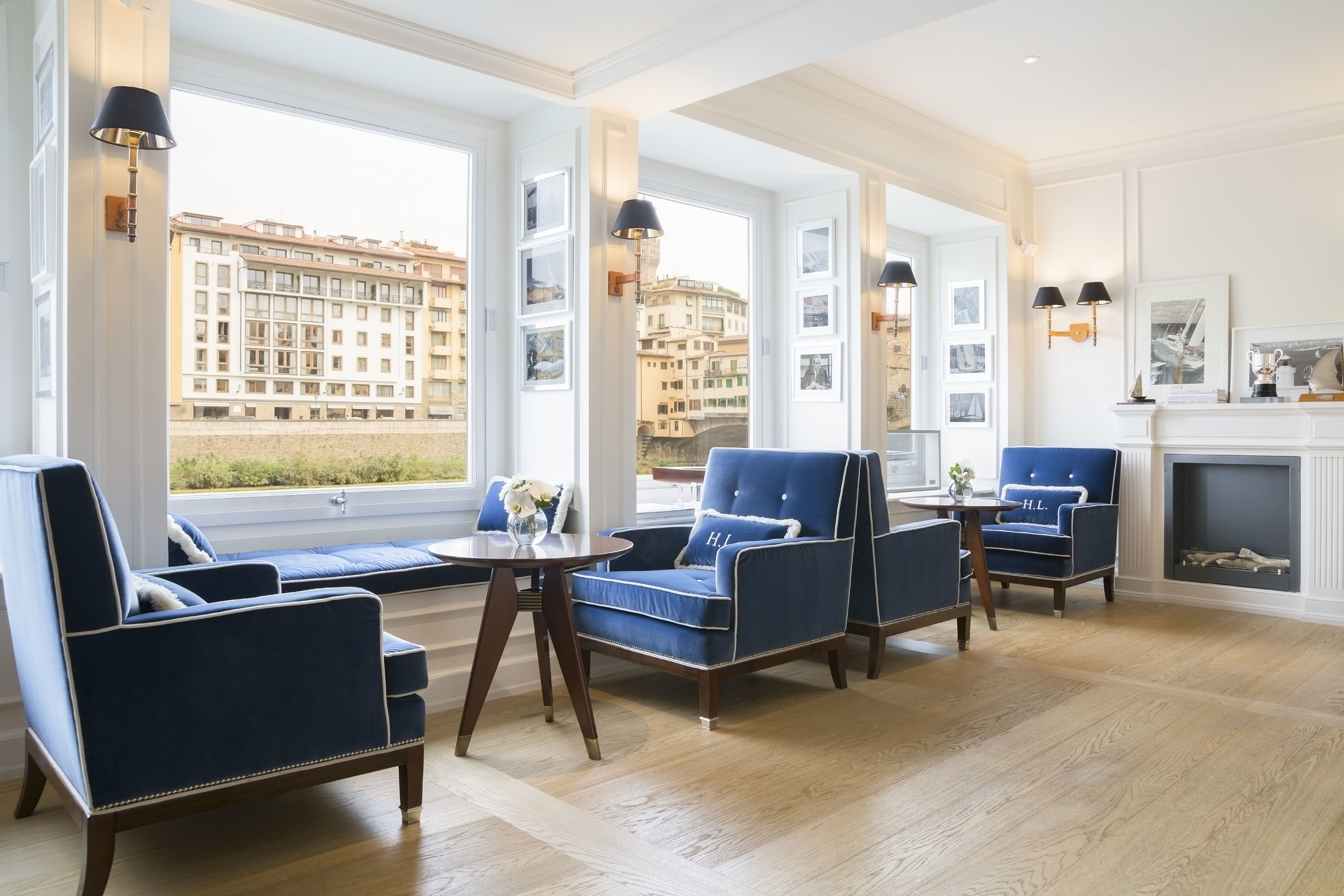 Hotel Lungarno lounge area with blue armchairs, a fireplace and river views