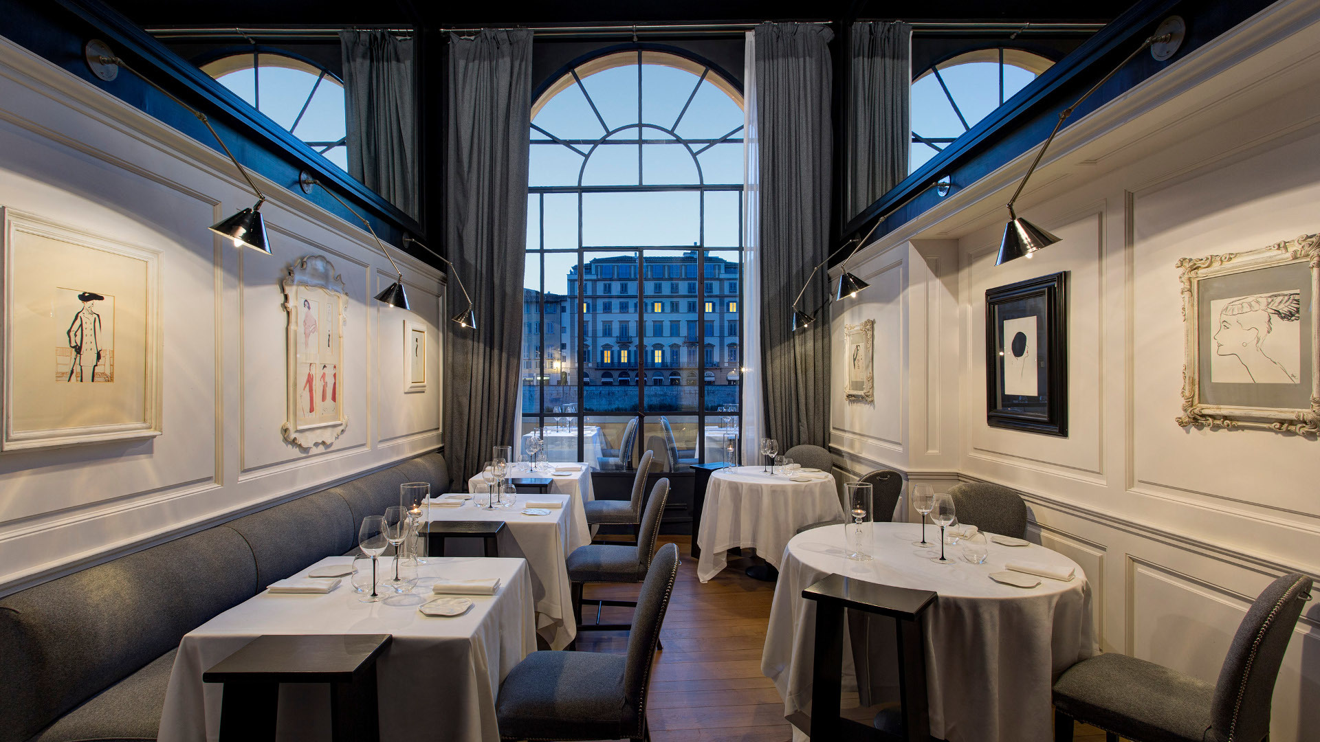 Hotel Lungarno Borgo San Jacopo Restaurant in white and blue, with tall arched windows looking out onto the river