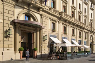 Beige stone exterior of grand hotel Savoy in Florence with awnings outside