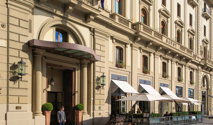 Beige stone exterior of grand hotel Savoy in Florence with awnings outside