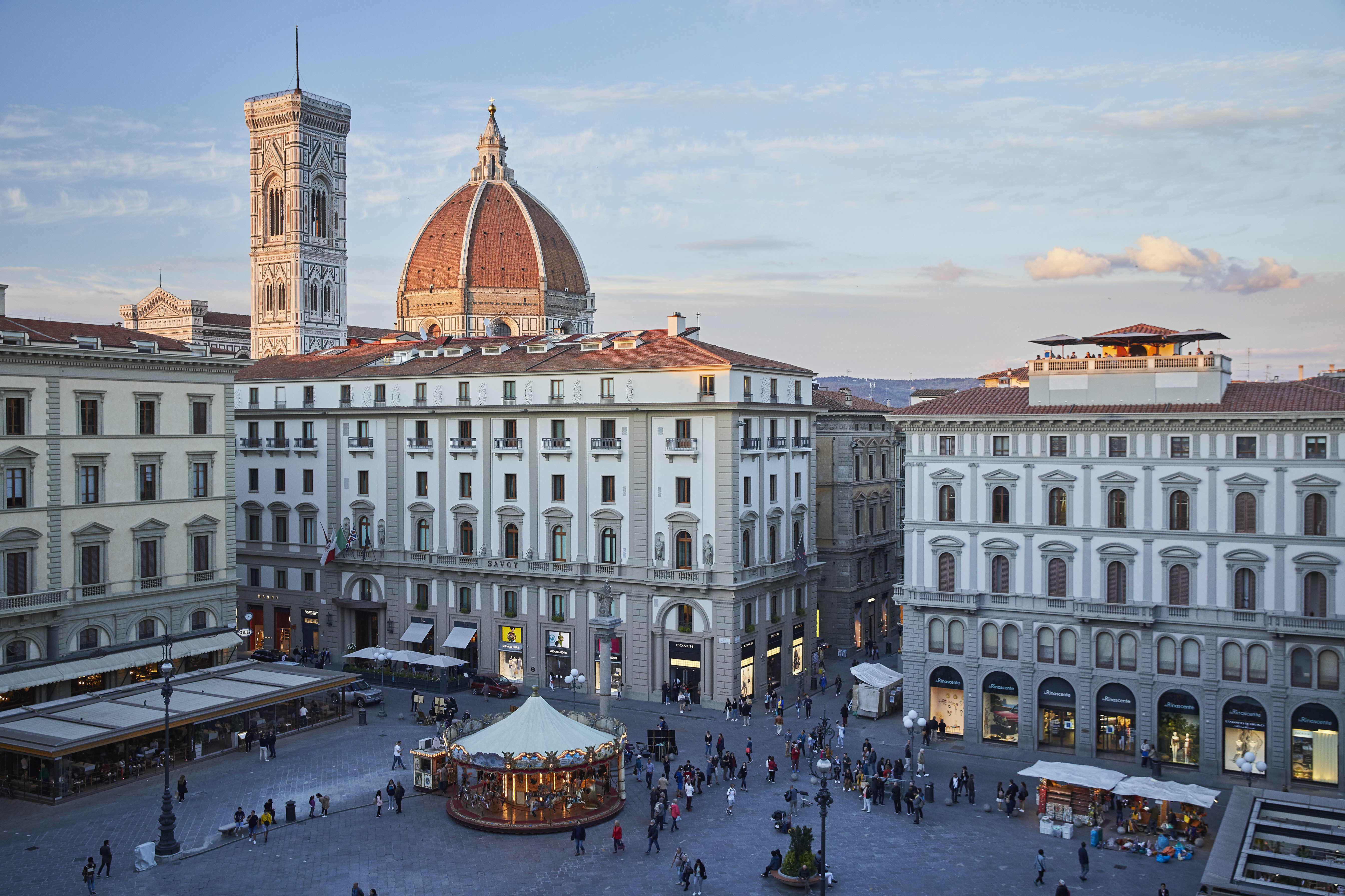 Elegant facade in white and grey of Hotel Savoy Florence with cathedral dome behind