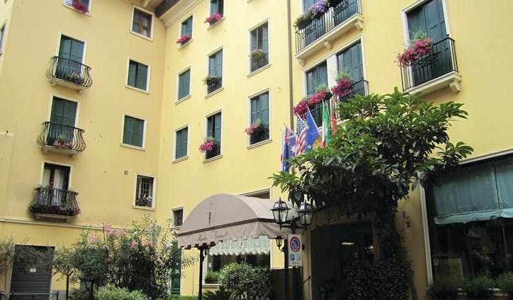 Majestic Toscanelli Padua hotel exterior yellow building juliet balconies window boxes with pink flowers
