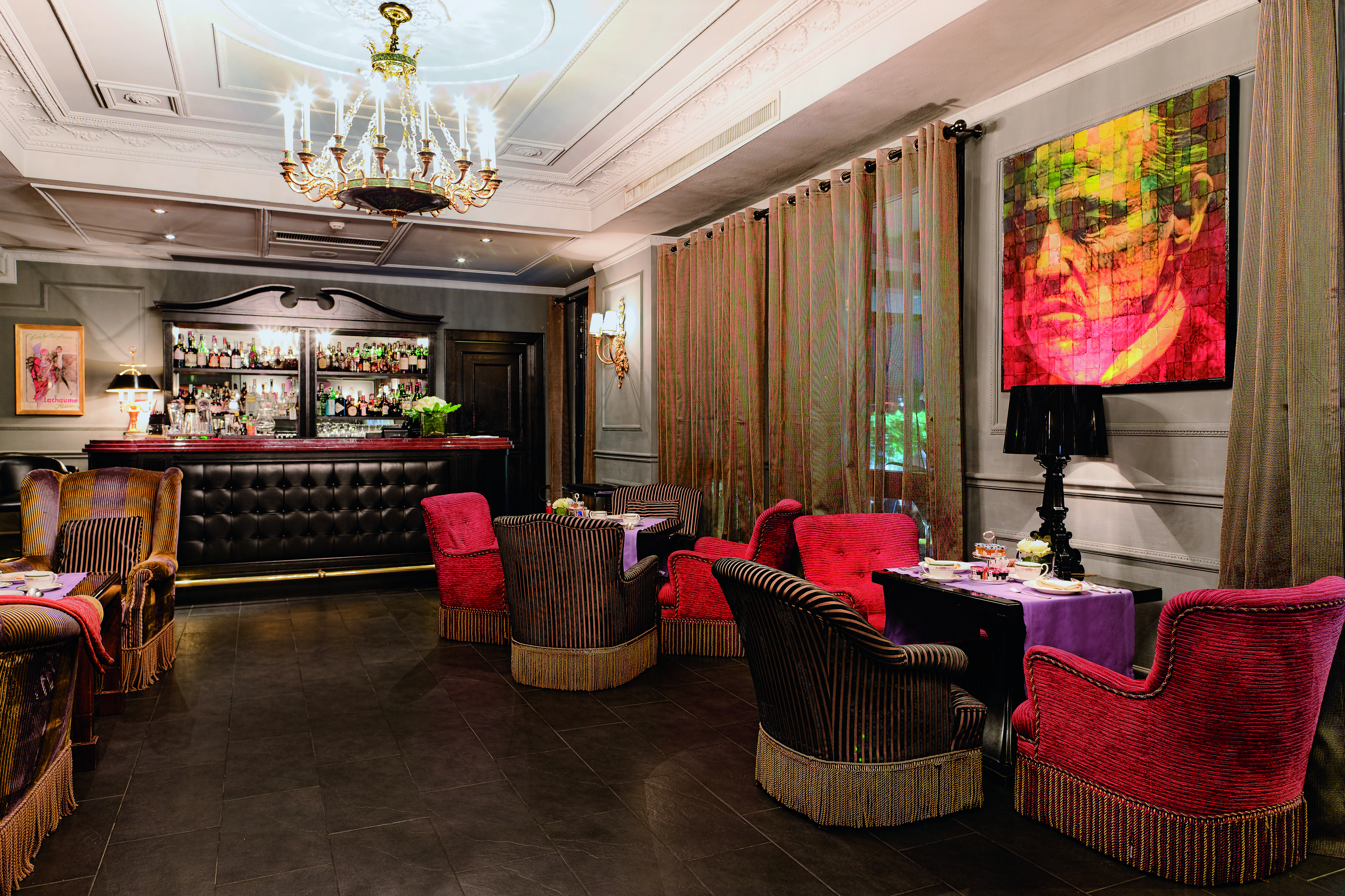 Bar and cafe at the Baglioni Hotel Carlton, with red and brown arm chairs placed around the wooden floors with a bar at the back of the room