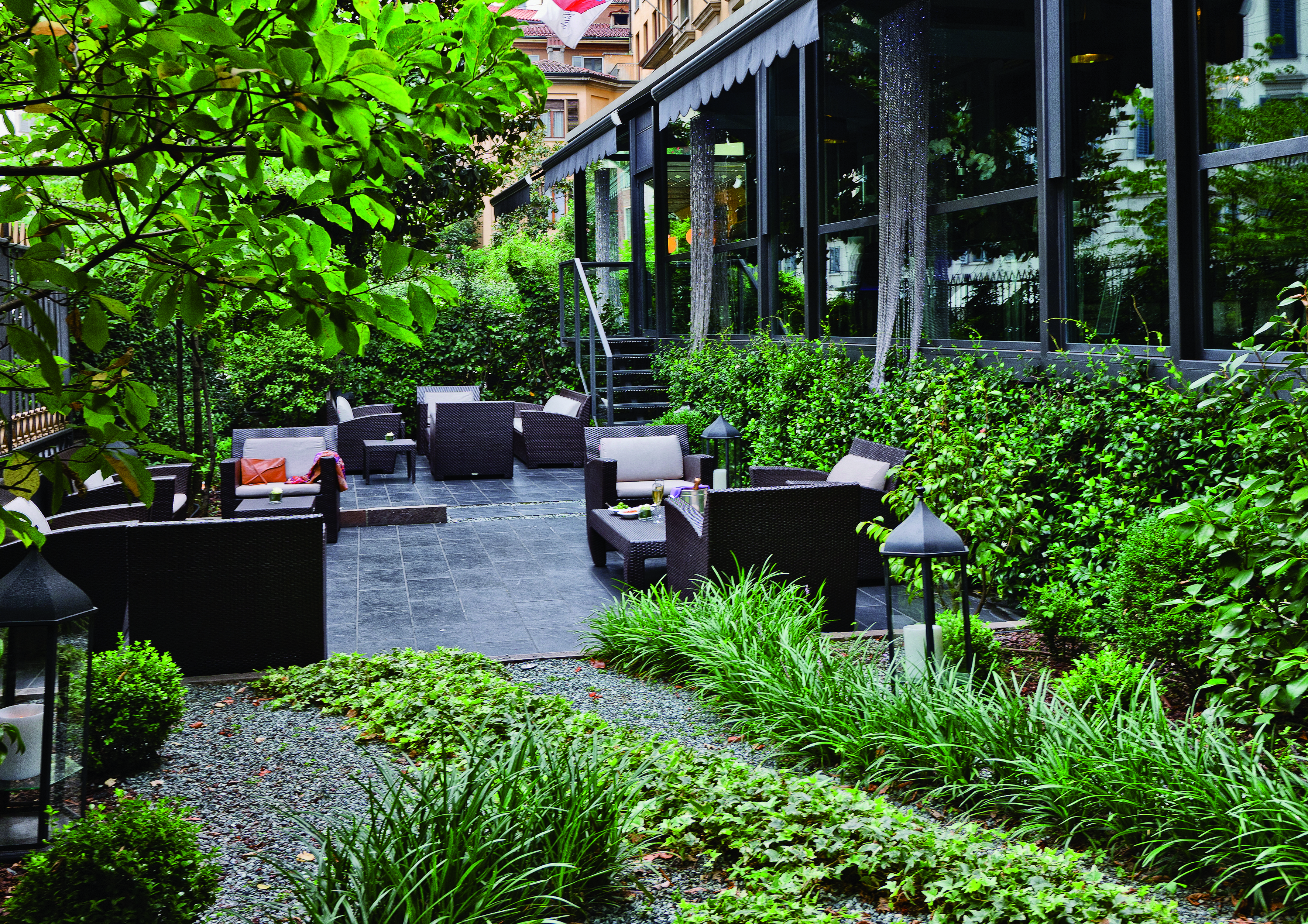Terrace gardens at the Baglioni Hotel Carlton with trees and greenery and scattered cushioned chairs 