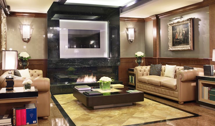 Baglioni Hotel Carlton lonny with leather sofas an electric fire and wooden wall pannels 