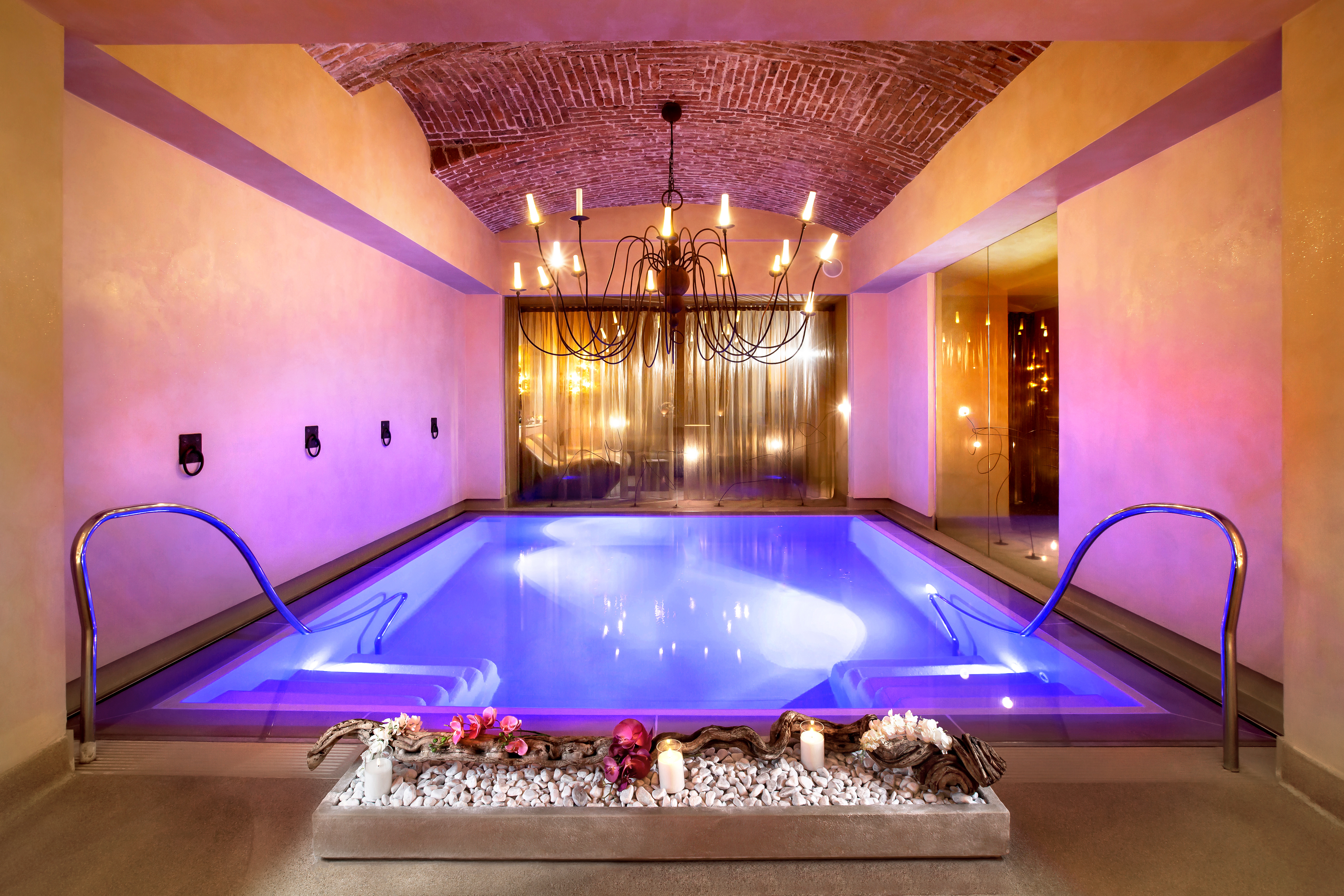 Chateau Monfort indoor pool, with lit water, and pink lit walls, and a chandelier