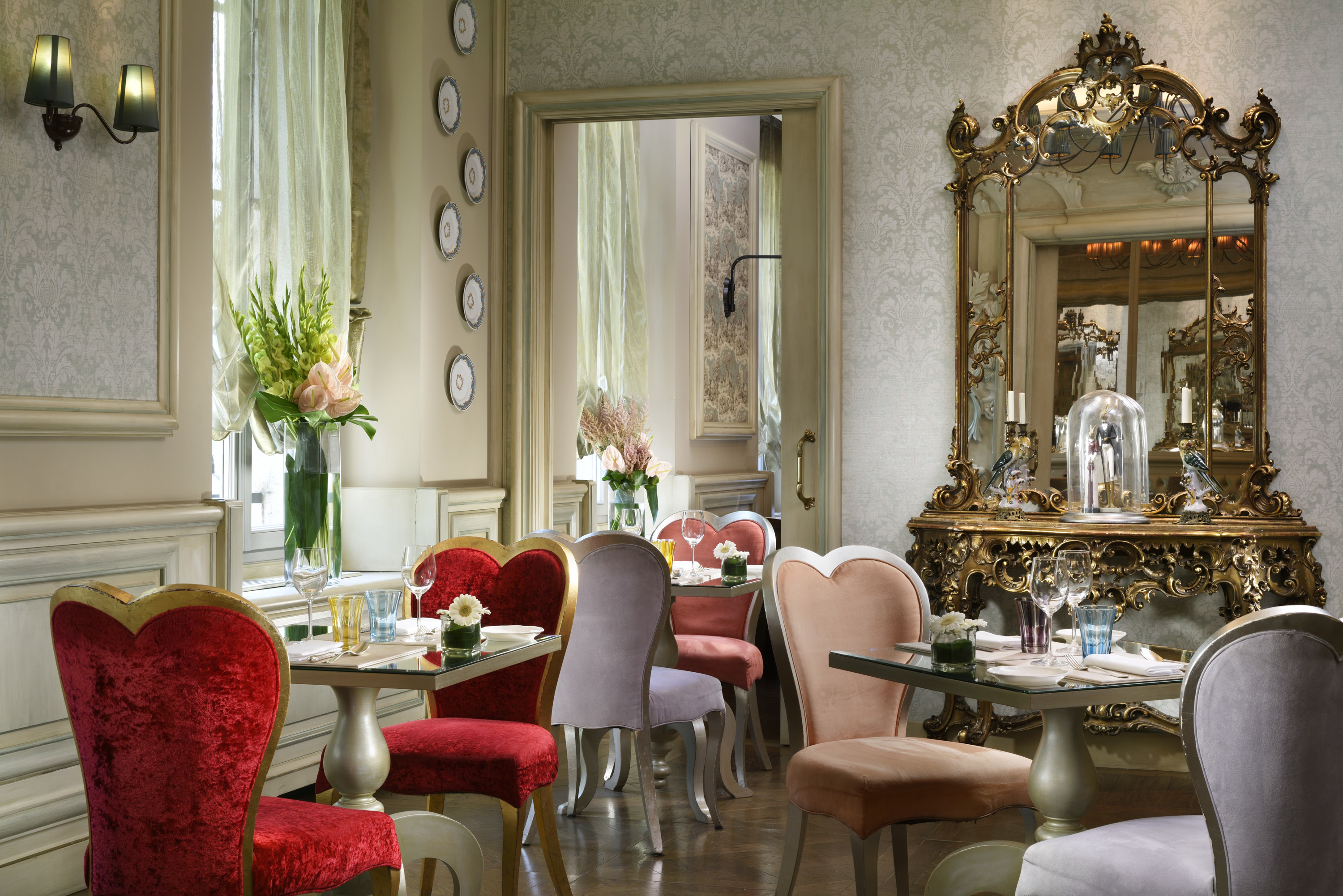 Chateau Monfort restaurant, with elegant soft heart-shaped chairs, a tall mirrored bar, and floral decorations
