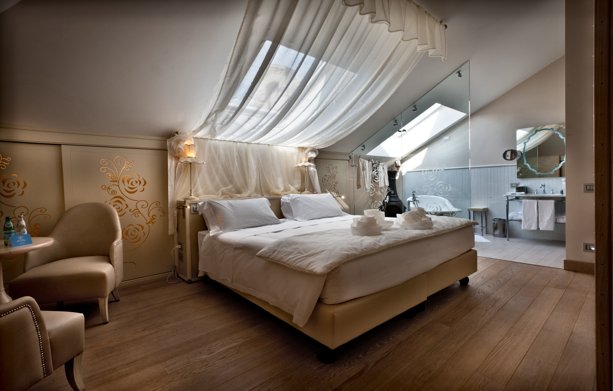 Chateau Monfort Suite Boheme, with neutral colour palette, drapes above the bed that filter light through the velux window, and open-plan bathroom