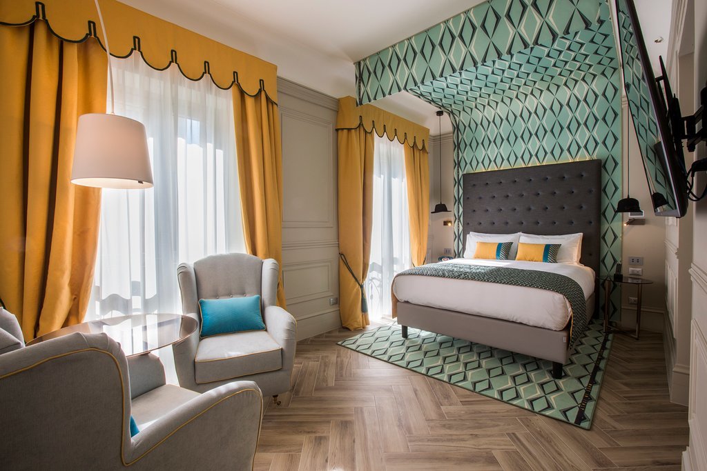 Hotel Indigo Milan room, with white and grey furnishings, embellished by a turquoise bed canopy and yellow curtains