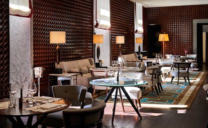 Hotel Portrait Milano 10_11 Bar with glass tables, white sofas, and textured red walls