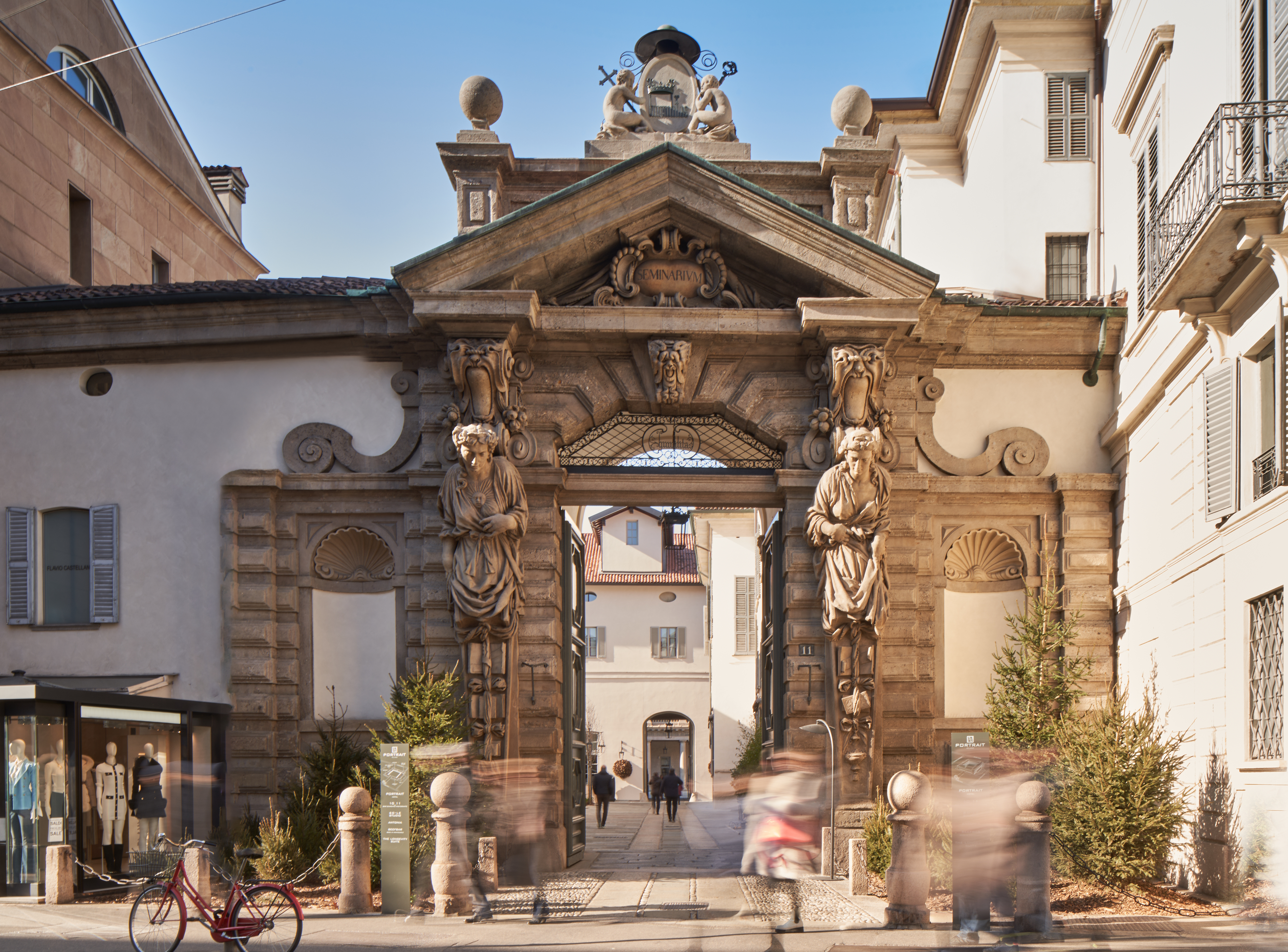Hotel Portrait Milano entrance, with ornate stone arch, statues, and white-washed buildings