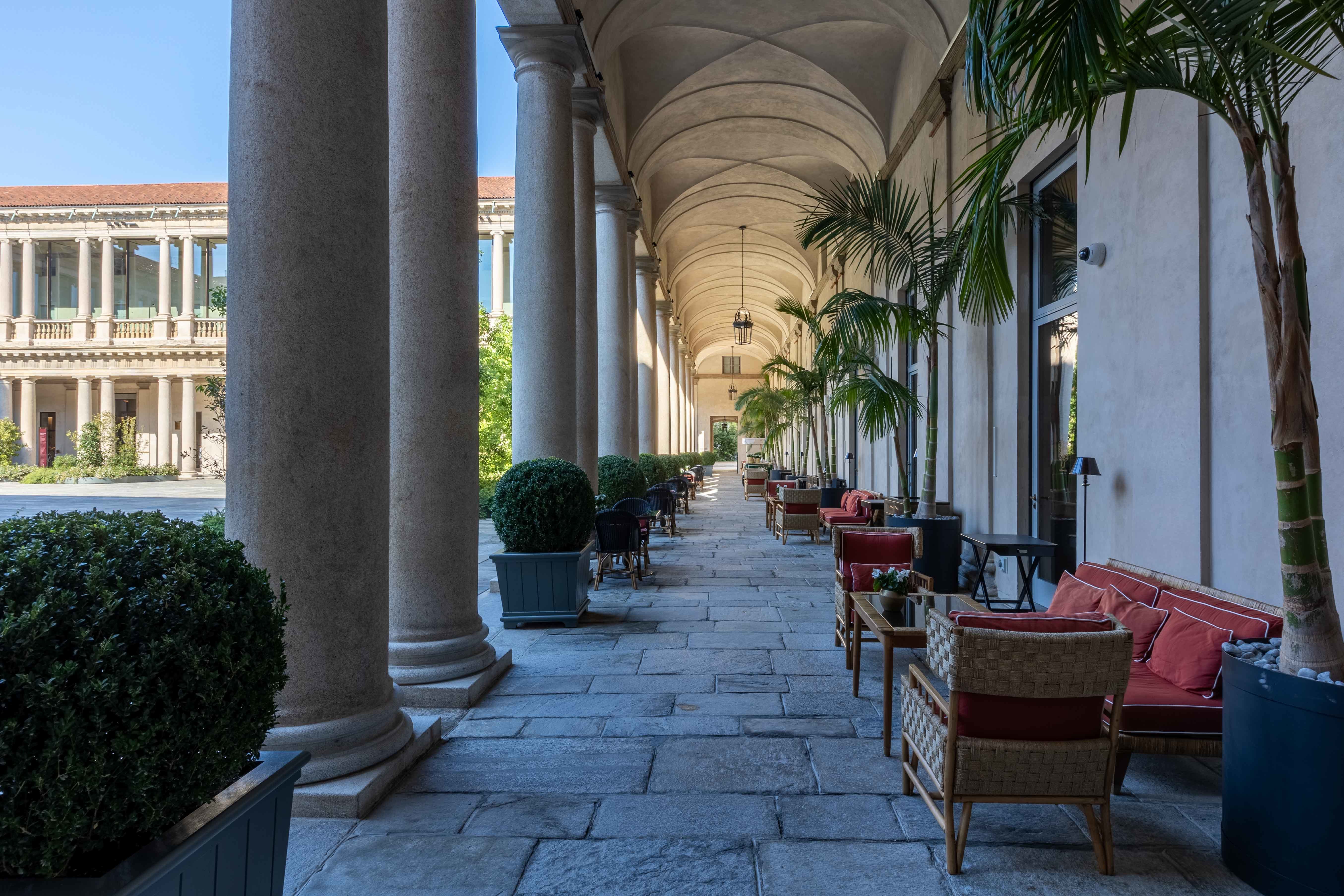 Hotel Portrait Milano portico around the central piazza, with comfortable red seating set behind the pillars
