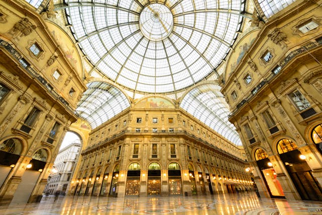 Ornate glass roof of the Galleria Vittorio Emanuele with elegant buildings in Milan