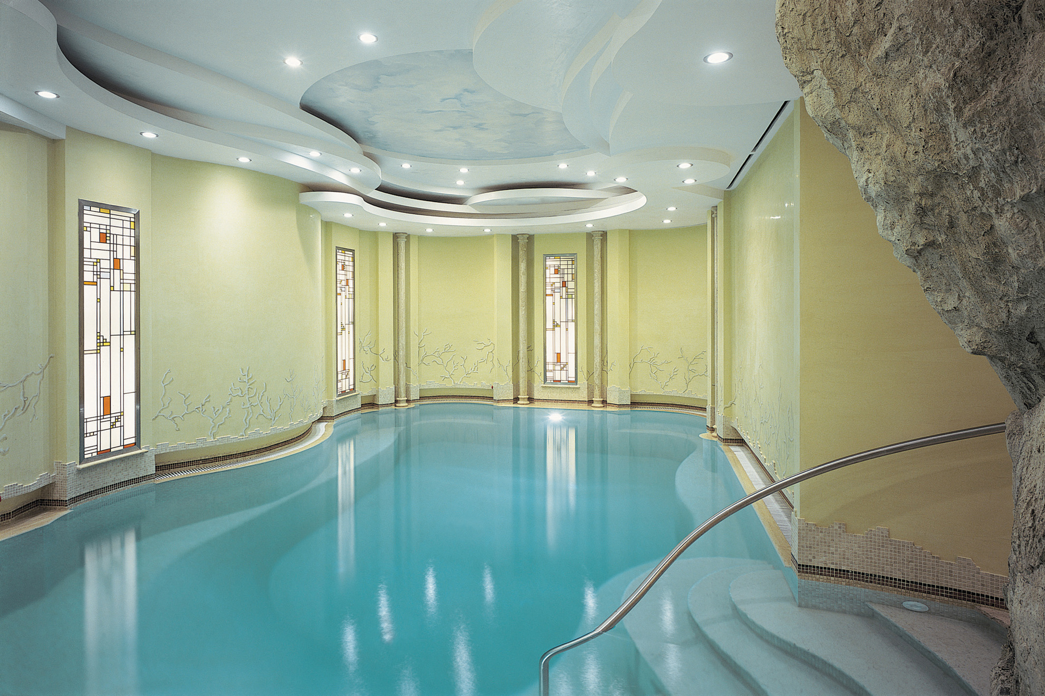 Indoor swimming pool with yellow walls and wall lights