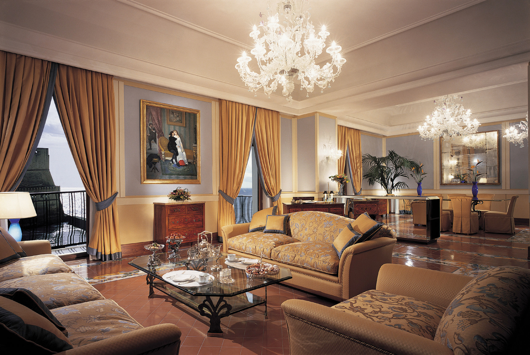 Lounge with large chandeliers, sofas and draping gold curtains