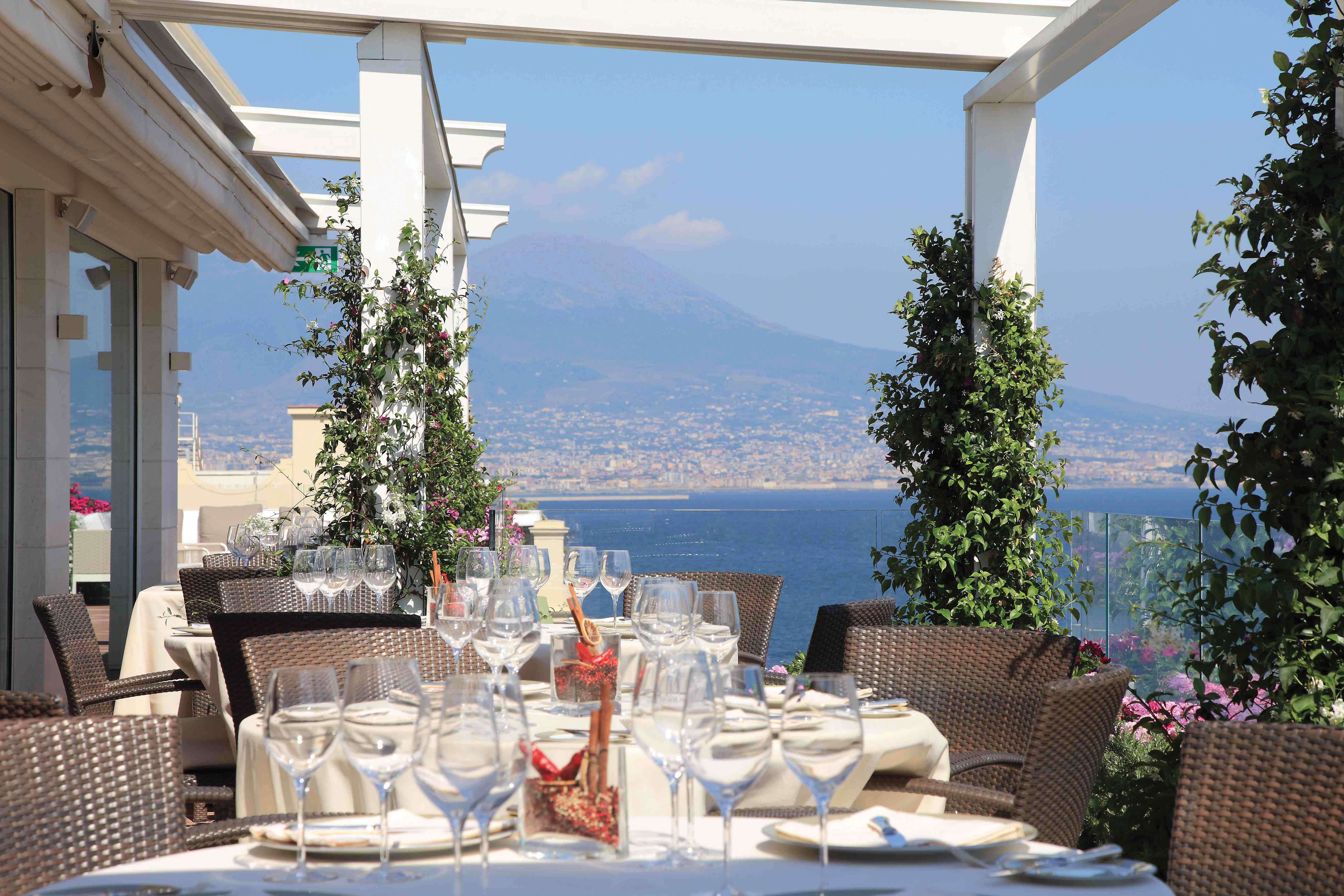 Outdoor restaurant dining area with views over mountains with tables set up on the terrace 