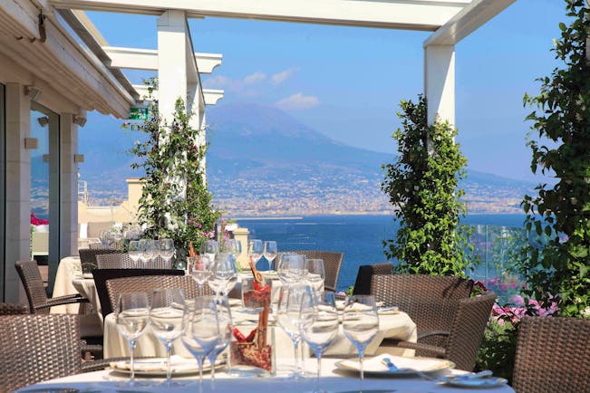 Outdoor restaurant dining area with views over mountains with tables set up on the terrace 