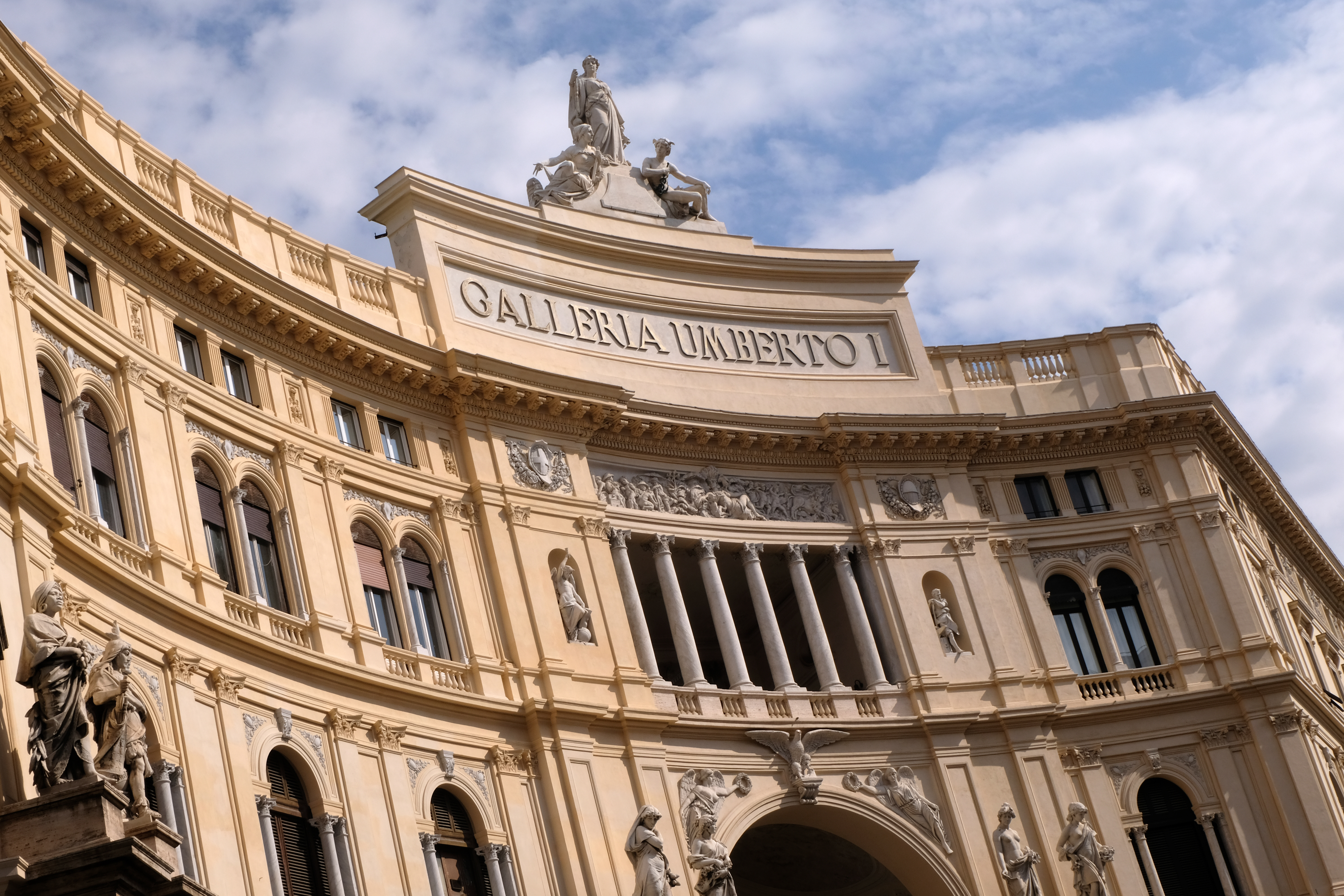Grand exterior of a civic building with rounded tall windows and statue on top